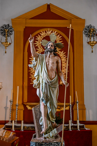 Statue of the Risen Christ with a white tunic and a cross cane.