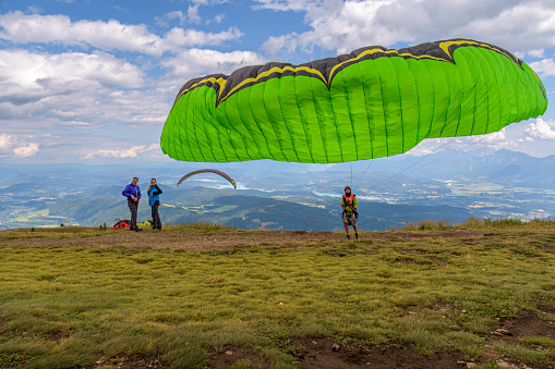 Treffen, Austria - August 4 2019: A paraglider waits until the wind is right to make a jump off the mountain, Gerlitzen.