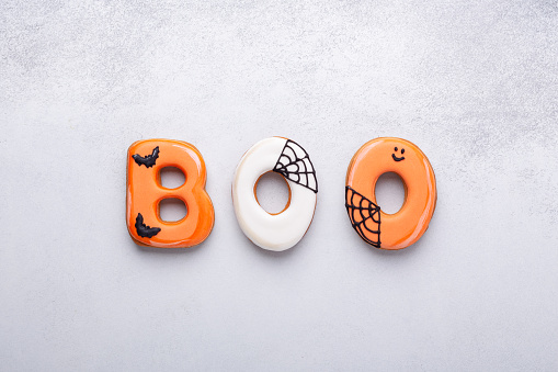 Text BOO from gingerbread cookies on white stone background. Halloween concept - Image