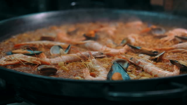 Close up slow motion view seafood paella cooked on frying pan