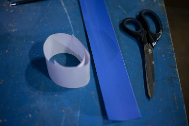 istock Scissors and paper on table. Items in workshop. Cutting strips. Use of adhesive tape. Things in room are blue. 1407900482