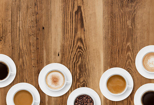 Coffee cups border on rustic wood background