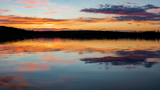 A  sunset's pastel colors are reflected in a Saskatchewan, Canada lake