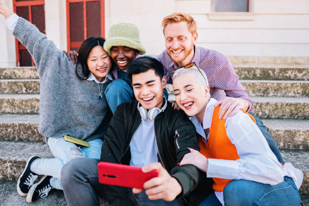 istock Five multiracial friends taking a picture with a smartphone smiling and having fun together sitting on the floor. 1407906565