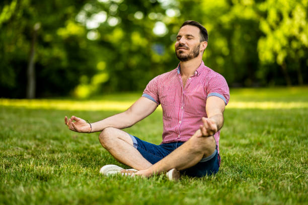 istock Young man meditating in the park in spring day. 1407907997