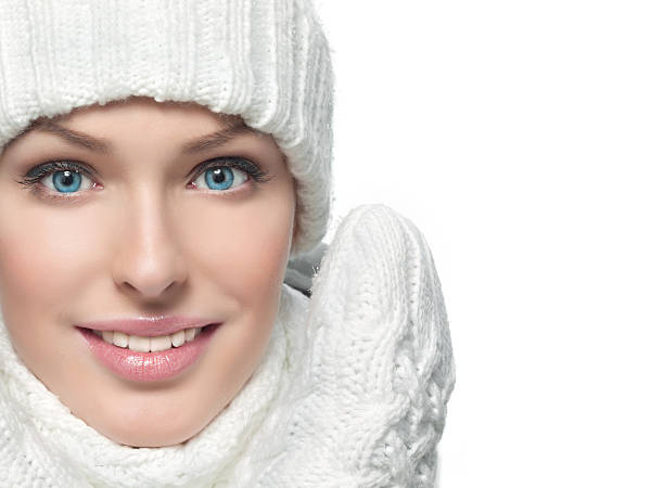 Closeup portrait of a woman in white hat, mittens, and scarf stock photo