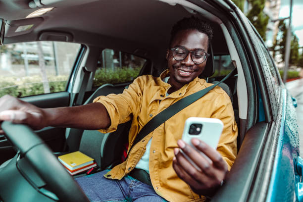 istock Happy young African-American man driving and using smart phone 1407921596