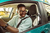 istock Happy African-American male driver driving a car and looking through the car window 1407921625