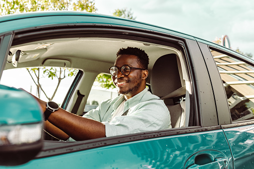 African-American young man driving a car and smiling