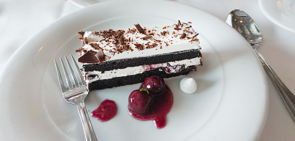 A slice of traditional Black Forest cake with cherries and chocolate garnish