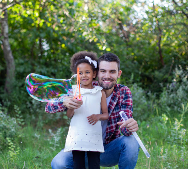 istock Happy father and daughter playing soap bubbles in park. 1407924882