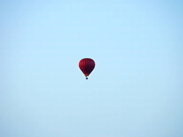 A hot air balloon flies against a beautiful sunset landscape.