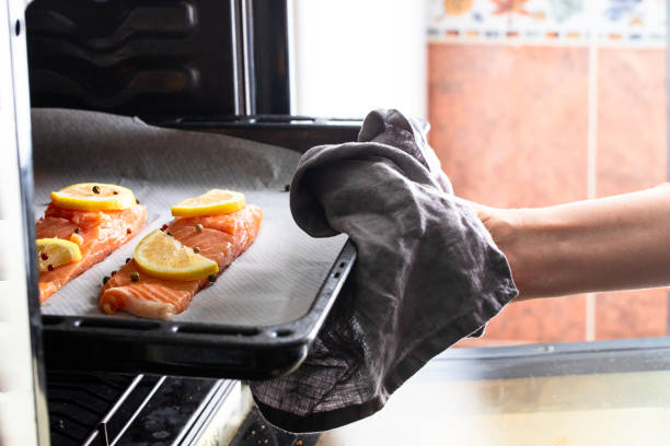 istock hand holding a oven try  with raw salmon slices with lemons and 1407931595