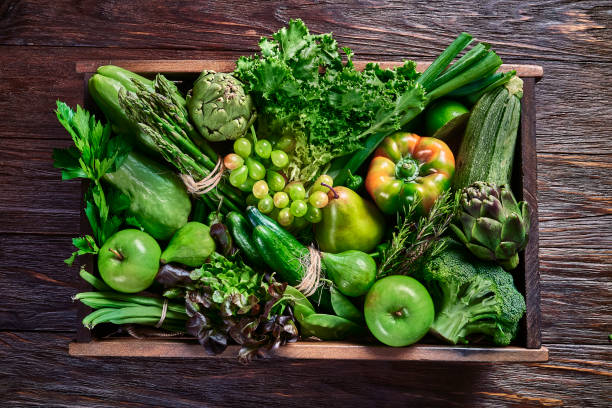 Vegan food themes. Table top view background of a variation green vegetables for detox and alkaline diet. Set in a crate on a wooden rustic table with a frame stock photo