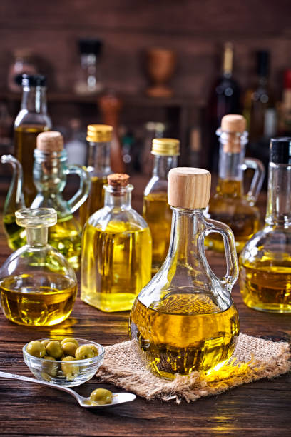 istock Olive oil bottle collection on wooden table in a old fashioned kitchen with low key illumination 1407935711