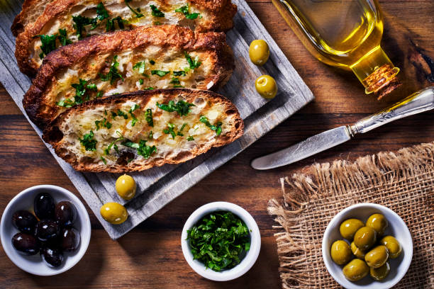 snack o aperitivo de albahaca de ajo y aceite de oliva bruschetta sobre mesa en una cocina rústica - bruschetta cutting board italy olive oil fotografías e imágenes de stock