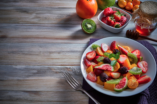 Vegan food themes. Close-up Top view of fresh multicolored tropical fruits bowl on rustic wooden table