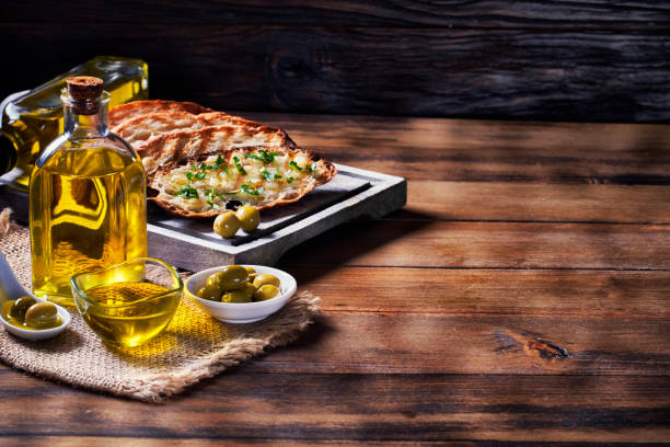 merienda o aperitivo de albahaca al ajo y bruschetta de aceite de oliva sobre mesa en una cocina rústica con espacio de copia - bruschetta cutting board italy olive oil fotografías e imágenes de stock