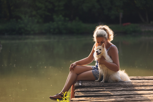 Middle age woman enjoying time with her dog near the lake