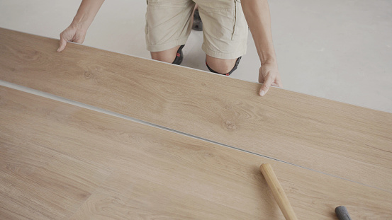 Man installing new timber laminated wooden floor, home improvement, house renovation project concept