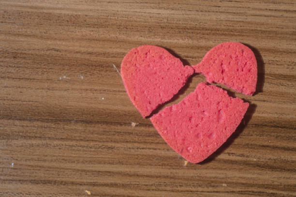 Broken heart work in pieces,broken heart-shaped biscuit on a wooden table.