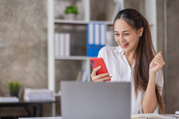 feliz joven asiática agitando las manos mirando la cámara web usando el teléfono para videollamada en casa, mujer de negocios sonriente divirtiéndose saludando en línea por teléfono cámara web haciendo videollamada a través de la aplicación - micromecenazgo fotografías e imágenes de stock