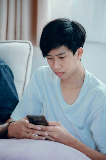 istock Young asian man playing a game on the phone with happiness 1407948291