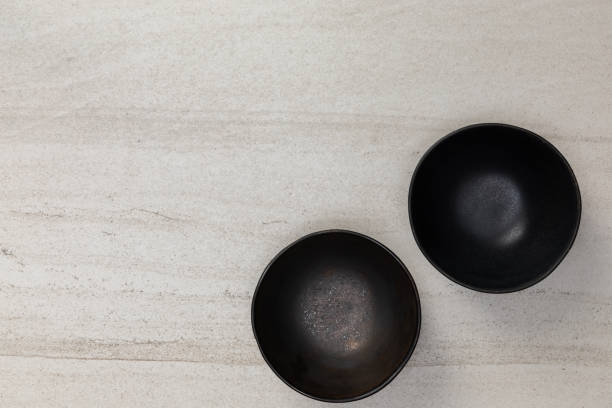 istock Group of empty blank black ceramic round bowls on white stone blackground, Top view of traditional handcrafted kitchenware concept 1407955059