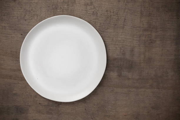 Blank white ceramic round dish on wooden desk blackground with copy space, Flat lay of traditional handcrafted kitchenware concept