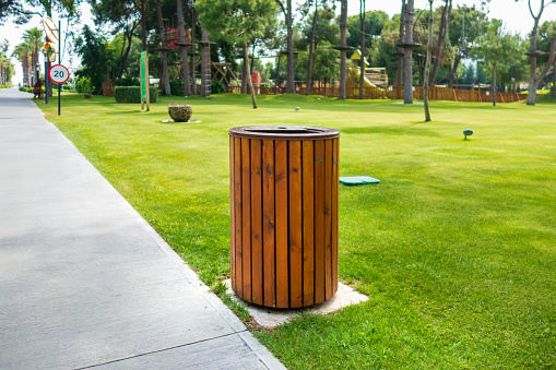 Wooden trash can next to the walkway in the park