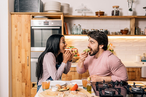 Cheerful black woman and her boyfriend having delicious breakfast in the kitchen at home.
