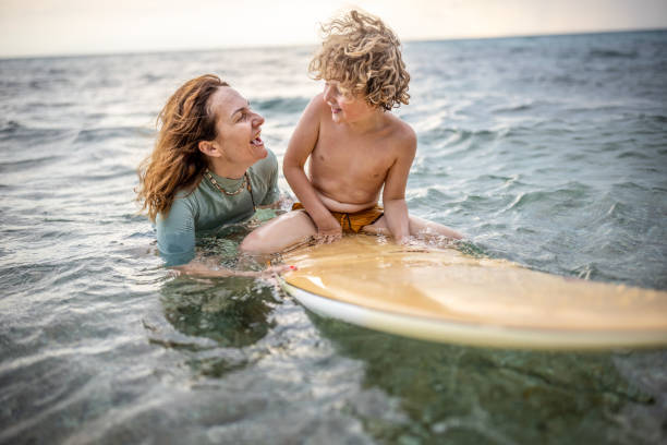 istock Little surfer learn to ride on surfboard with mother 1407958165