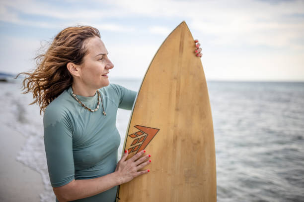 istock Surfer woman on a beach with surfboard 1407958274