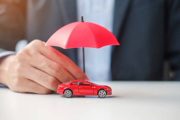 homme d’affaires tenant un parapluie et un jouet de voiture rouge sur la table. assurance auto, garantie, réparation, financier, bancaire et financier - toy umbrella photos et images de collection