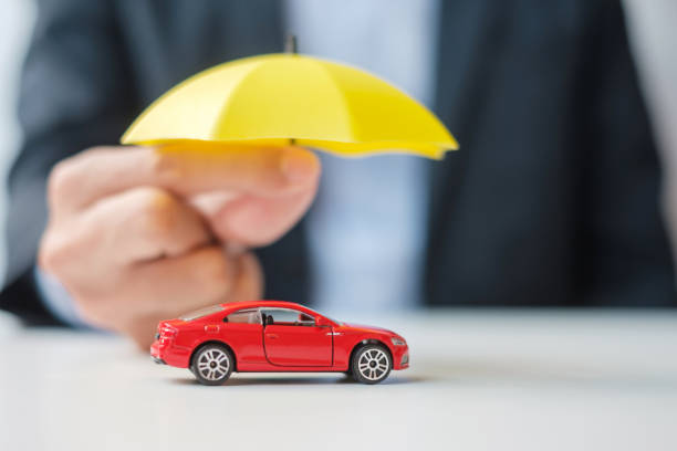 homme d’affaires tenant un parapluie et un jouet de voiture rouge sur la table. assurance auto, garantie, réparation, financier, bancaire et financier - toy umbrella photos et images de collection