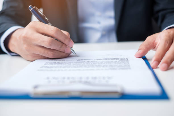 istock man signing on contract documents after reading, man holding pen and approve on business report. Contract agreement, law and deal concepts 1407961298