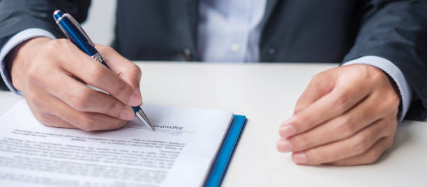 istock man signing on contract documents after reading, man holding pen and approve on business report. Contract agreement, law and deal concepts 1407961299