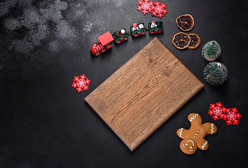 Christmas homemade gingerbread cookies, spices and cutting board on dark background with copy space for text top view