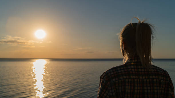 istock Young woman watching the sunset over the river 1407963592