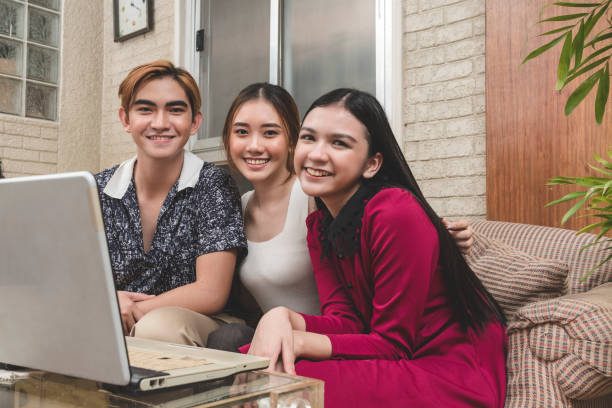 Three friends hanging out on the sofa, working on a group project for school. Teamwork concept.