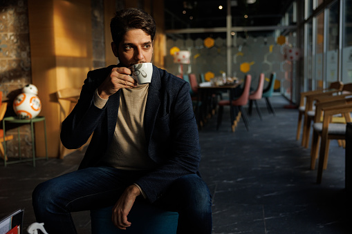 Attractive young man enjoying cup of coffee in coffee shop