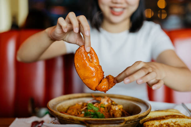 donna asiatica sorridente che tiene un artiglio di aragosta nel ristorante - gourmet food lobster seafood foto e immagini stock