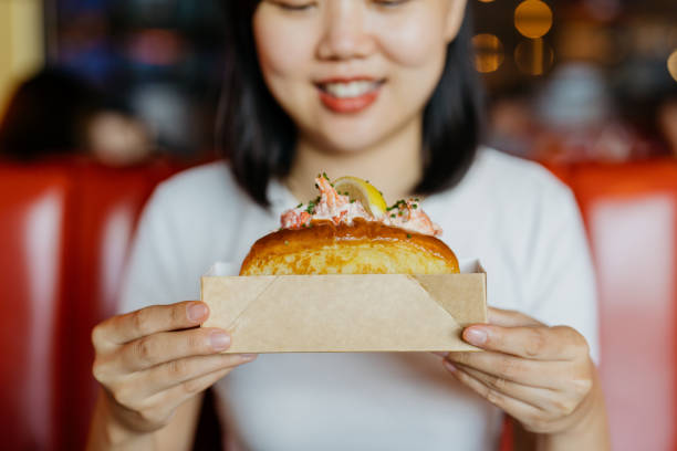 uma mulher asiática segurando rolo de lagosta em um recipiente de papel - freedom sandwich bread food - fotografias e filmes do acervo