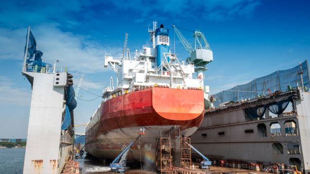 a pintura do casco consiste na lavagem, detonação e pintura do navio de carga do navio por operador no serviço internacional de manutenção do conceito de doca seca. - industrial ship shipping painting repairing - fotografias e filmes do acervo