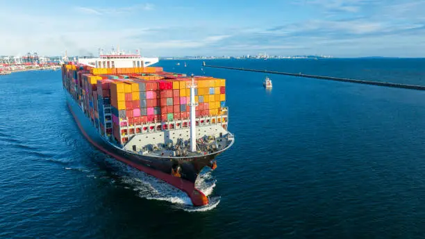 Photo of Aerial side view of cargo ship carrying container and running for export  goods  from  cargo yard port to custom ocean concept technology transportation , customs clearance.