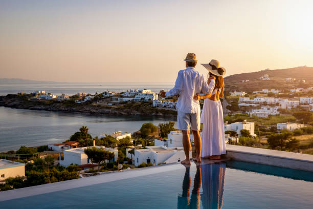 feliz pareja en tiempo de vacaciones disfruta de la puesta de sol de verano sobre el mar egeo - romantic getaway fotografías e imágenes de stock