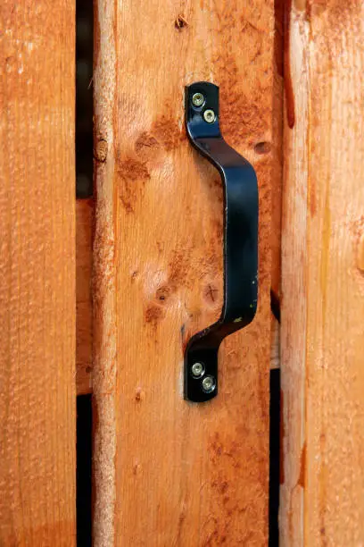 Black door handle on wooden plank door. Architectural details in countrystyle.