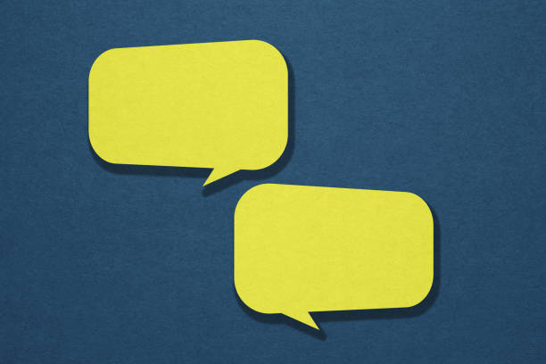istock two blank yellow speech bubble paper cut ,including clipping path on blue paper background. Conceptual image about communication and social media 1407979703