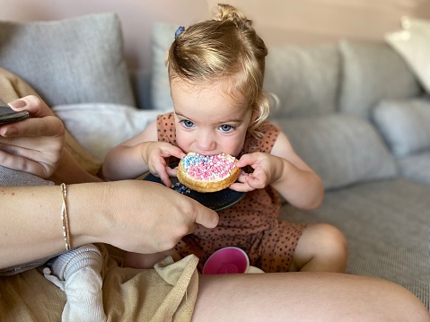 Cute toddler girl eating rusk with colored candy for the birth of her twin brother and sister