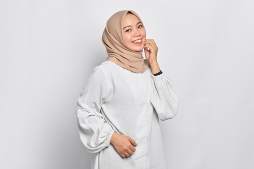 Smiling young Asian Muslim woman feels confident and joyful isolated over white background